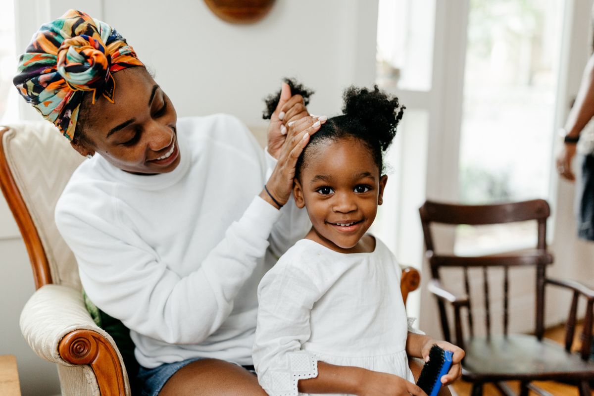 Mother applying Leave-In Conditioner on daughter